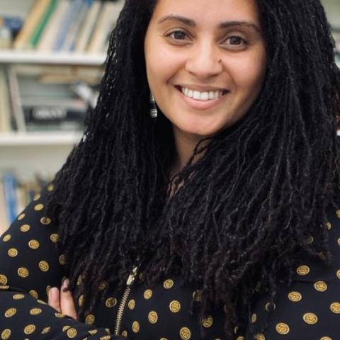 woman in printed black shirt standing in front of a bookcase